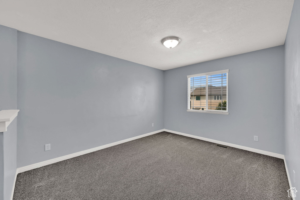 Empty room with carpet and a textured ceiling