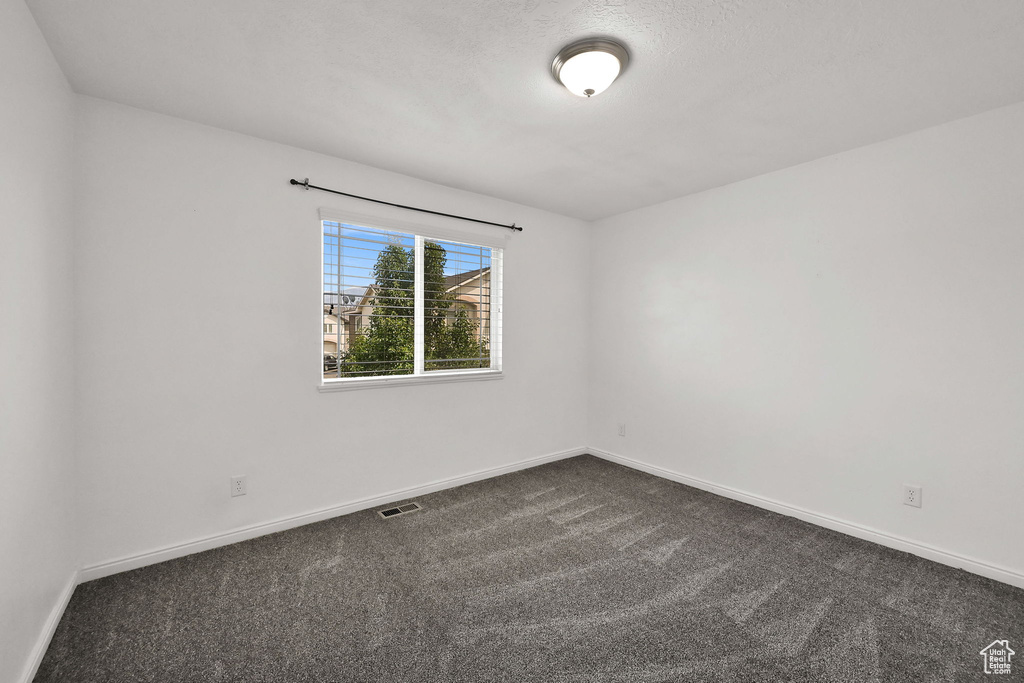 Unfurnished room featuring dark carpet and baseboards