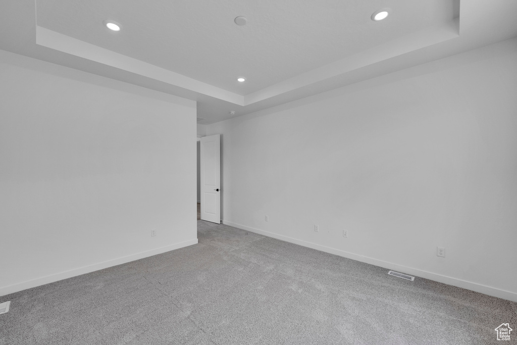 Carpeted spare room with a tray ceiling and recessed lighting