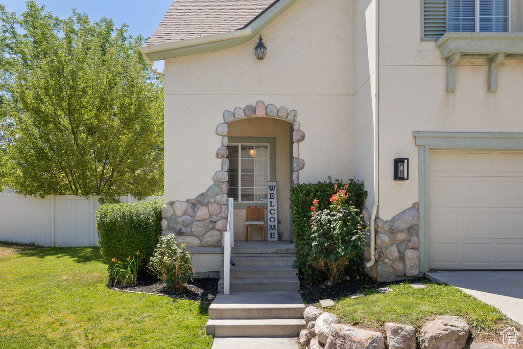 Doorway to property featuring stone siding, stucco siding, and a garage