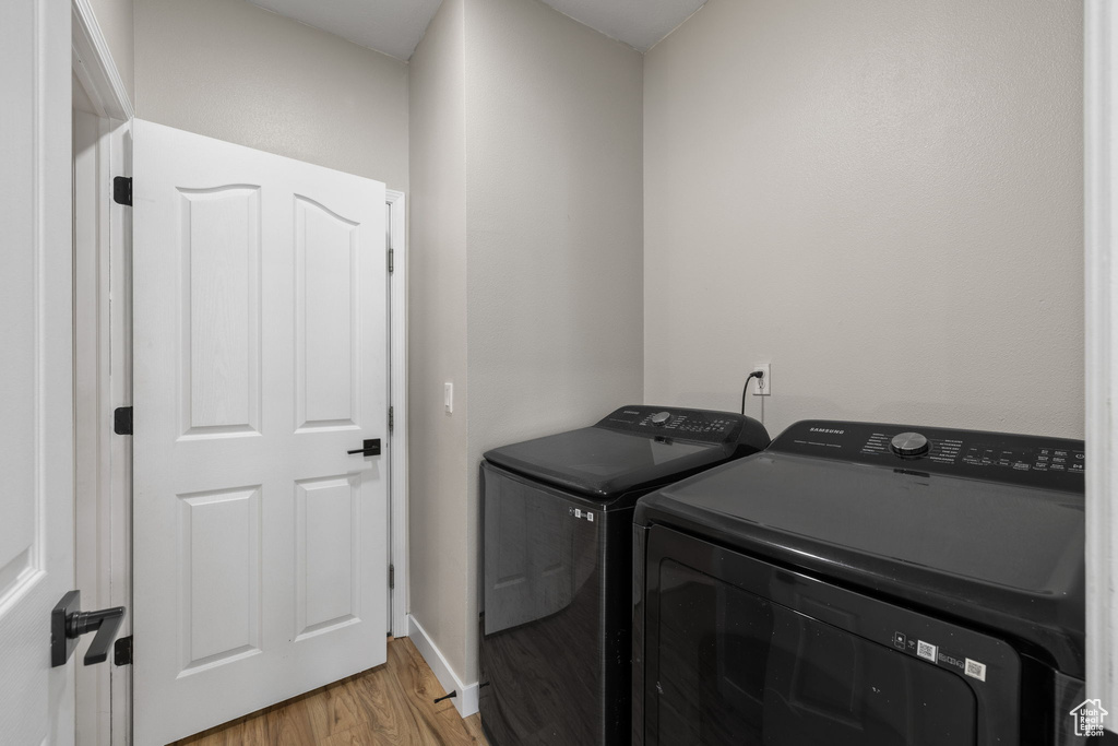 Washroom featuring washer and dryer and light wood finished floors