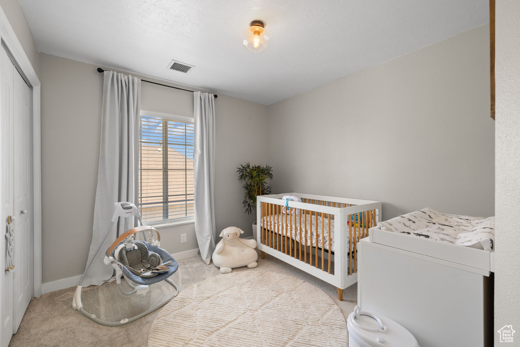 Carpeted bedroom with a crib and a closet