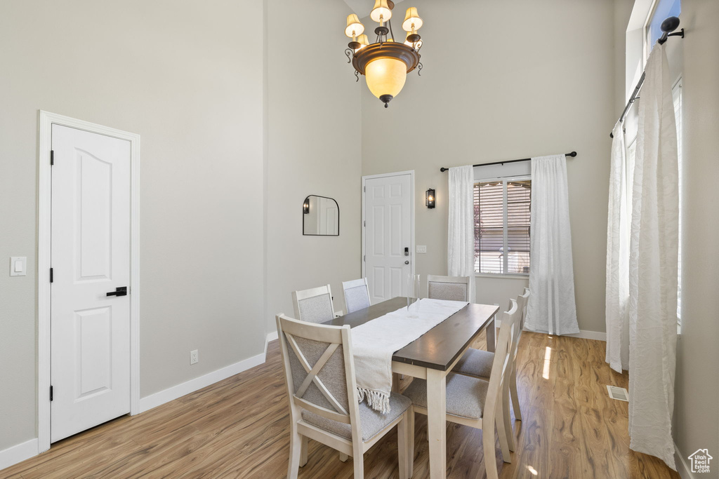 Dining space featuring a towering ceiling, a chandelier, and light wood finished floors