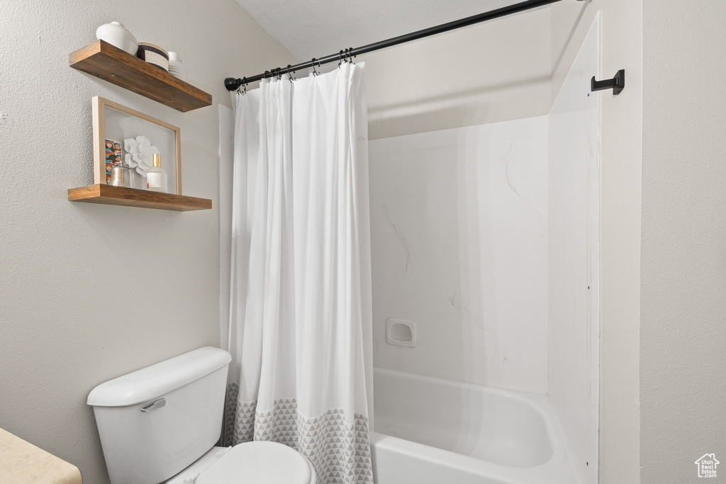 Full bathroom with toilet and shower / bath combination with curtain