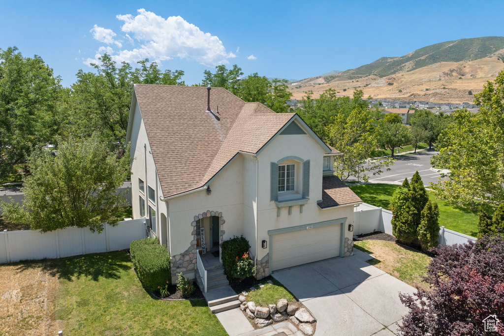 View of front of house with stucco siding, roof with shingles, stone siding, concrete driveway, and a garage