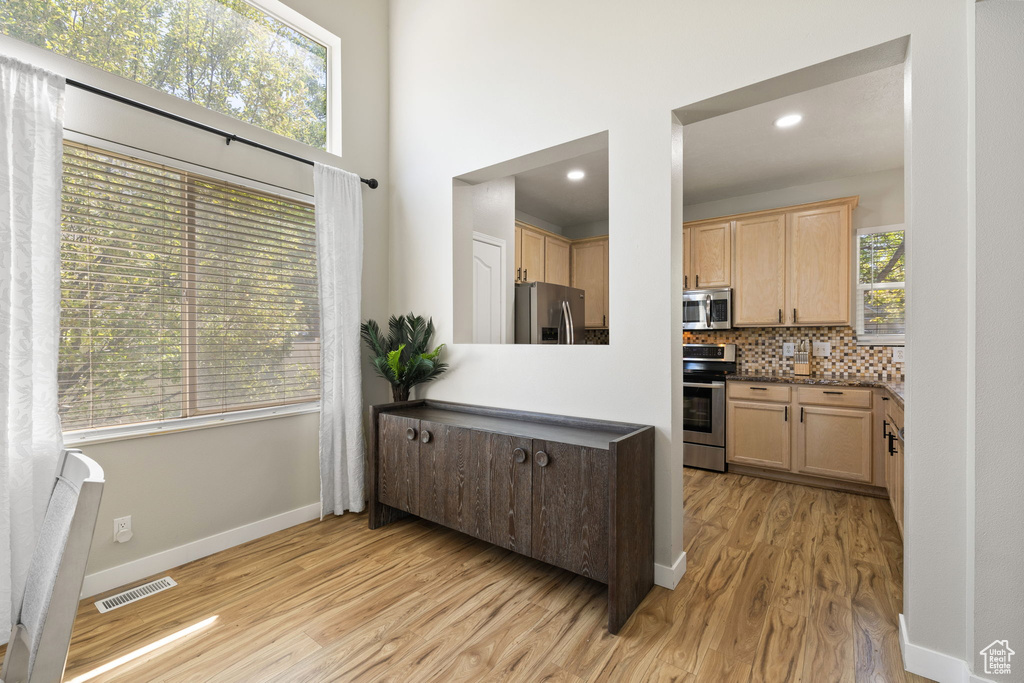 Kitchen with appliances with stainless steel finishes, light wood finished floors, light brown cabinetry, tasteful backsplash, and recessed lighting