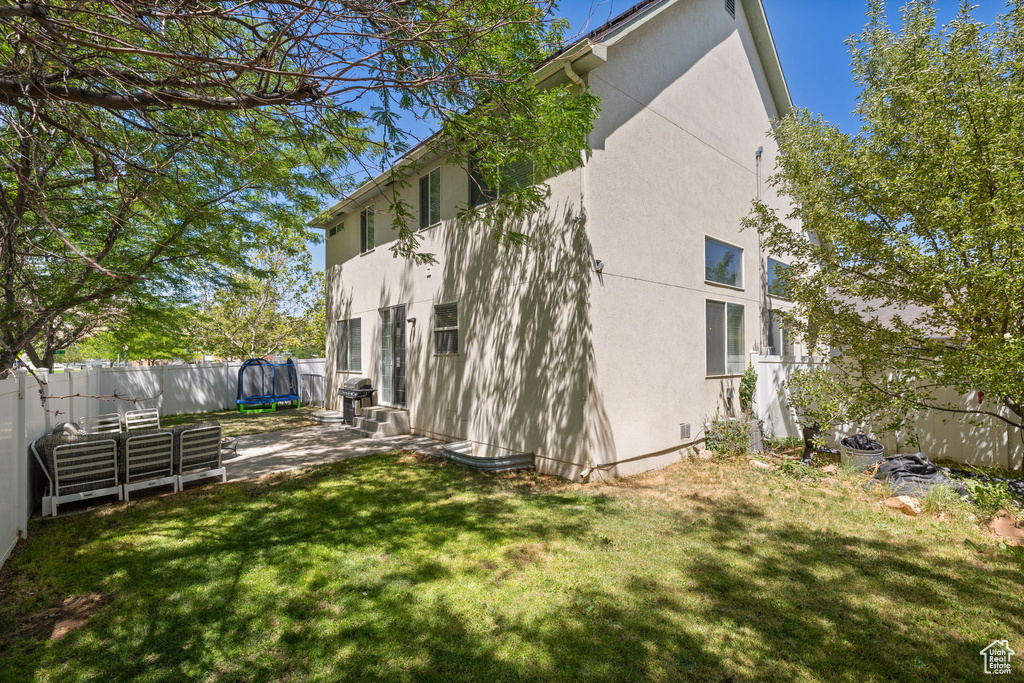 View of home\'s exterior with a trampoline, stucco siding, and a fenced backyard