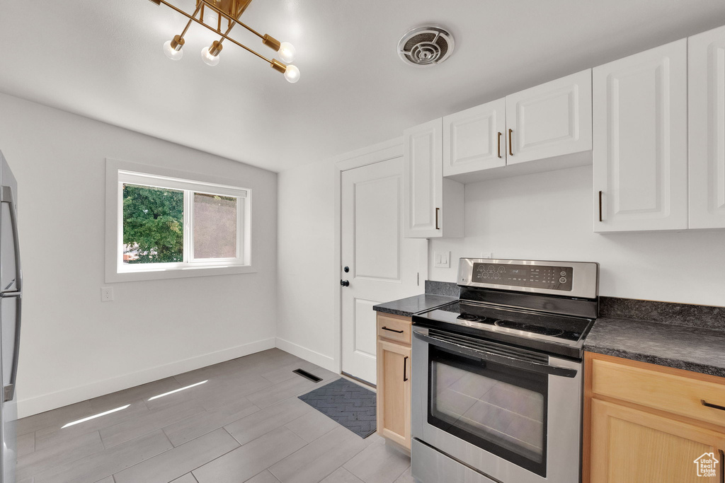 Kitchen featuring appliances with stainless steel finishes, dark countertops, and white cabinetry
