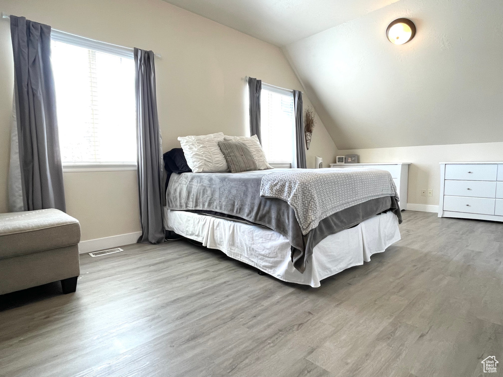 Bedroom featuring wood finished floors and vaulted ceiling
