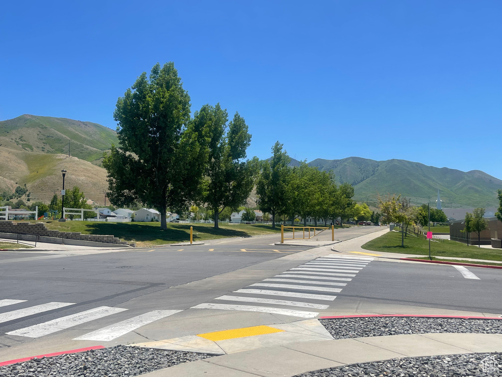 View of asphalt street with a mountain view, curbs, street lighting, and sidewalks