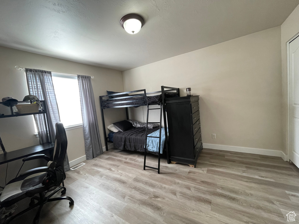 Bedroom with light wood-style floors and an office area