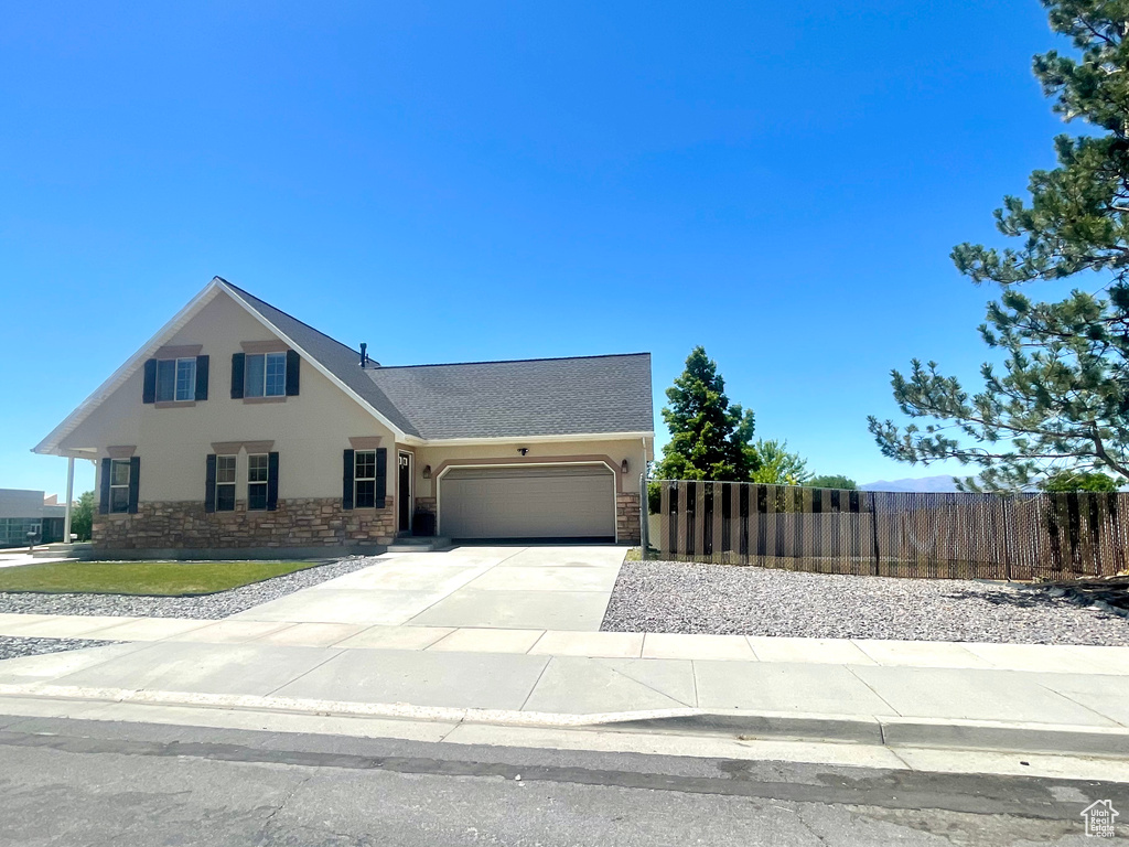 View of front of home featuring stucco siding, a garage, concrete driveway, and stone siding