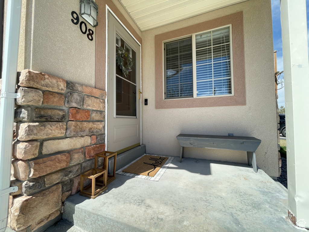 Property entrance with covered porch, stone siding, and stucco siding