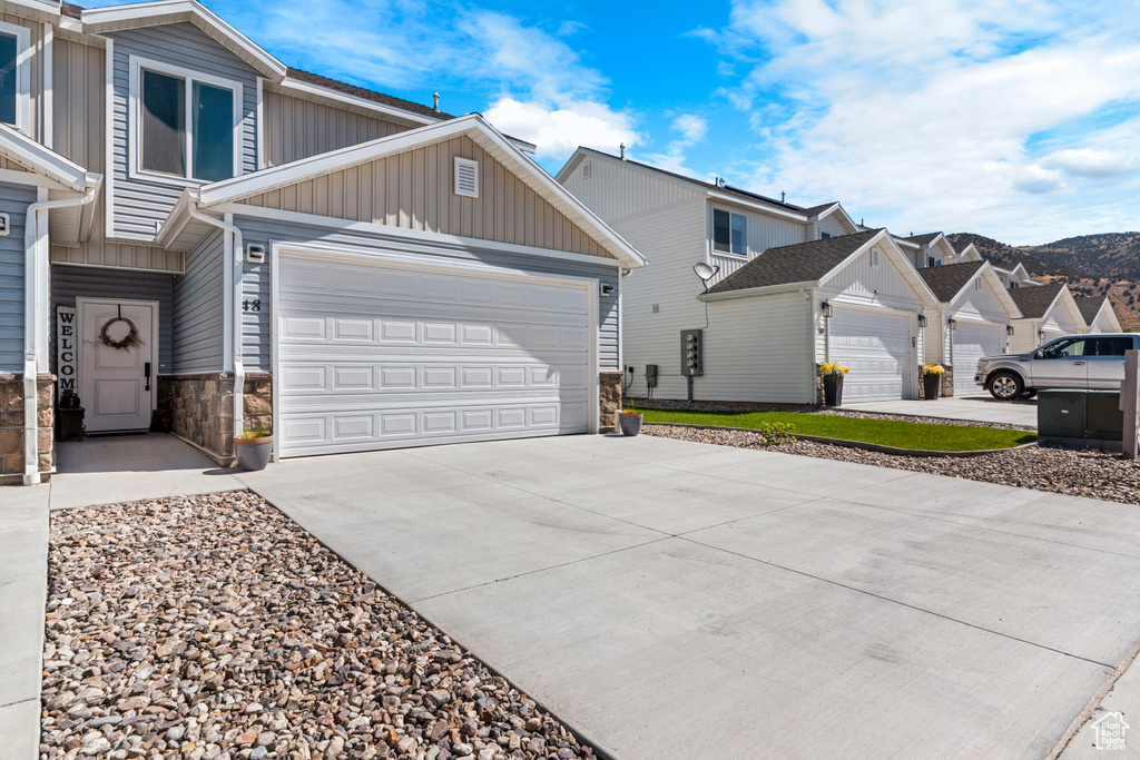 View of front of house with board and batten siding, driveway, a garage, and stone siding