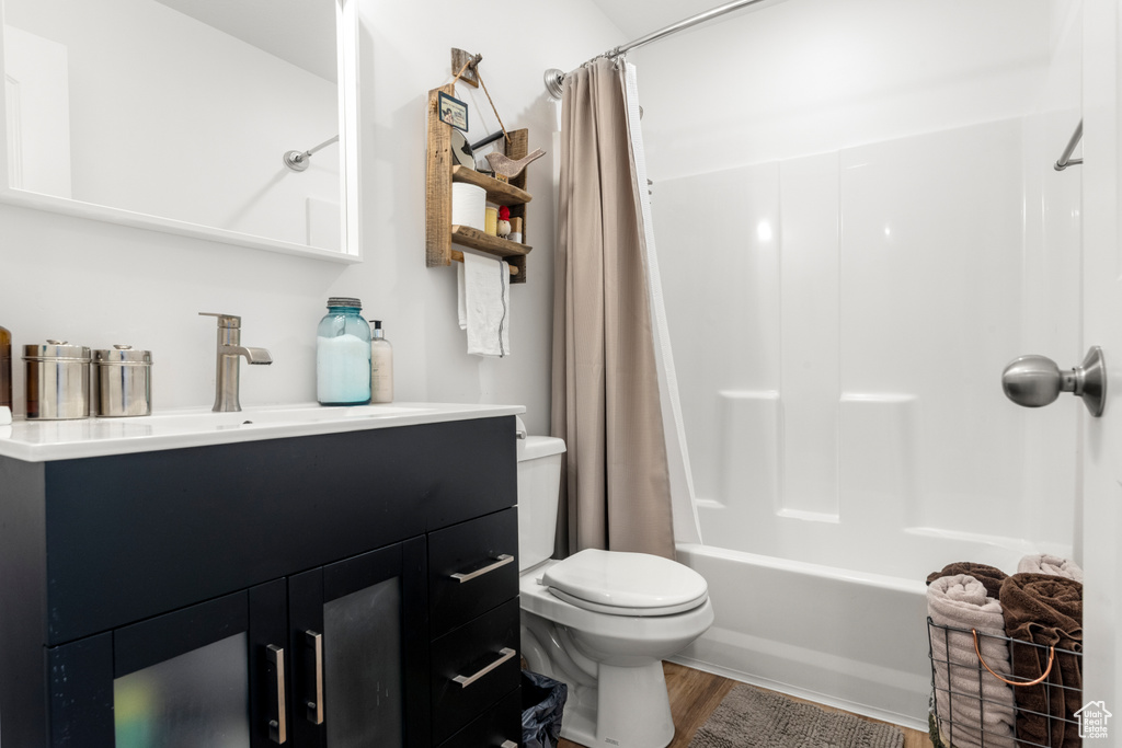 Full bath featuring vanity, shower / bath combo with shower curtain, and wood finished floors