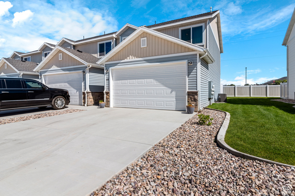 View of front of home with board and batten siding, driveway, an attached garage, and stone siding