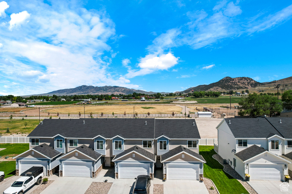 View of front facade featuring a mountain view, board and batten siding, driveway, a residential view, and stone siding