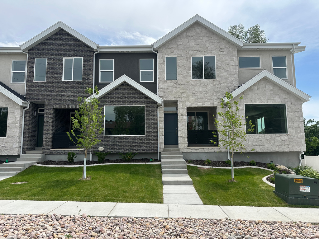 View of front of property with stone siding and a front yard