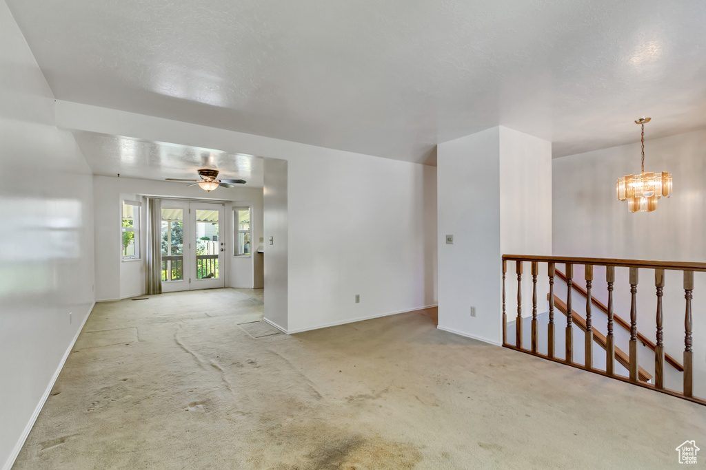 Empty room with carpet floors, a chandelier, and a ceiling fan