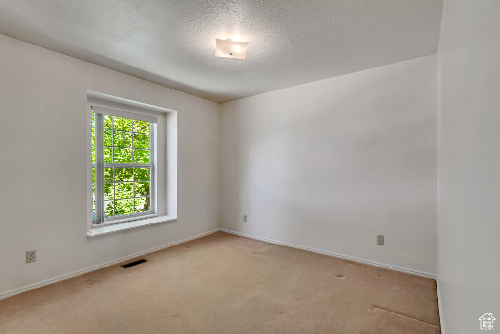 Carpeted spare room with baseboards and a textured ceiling