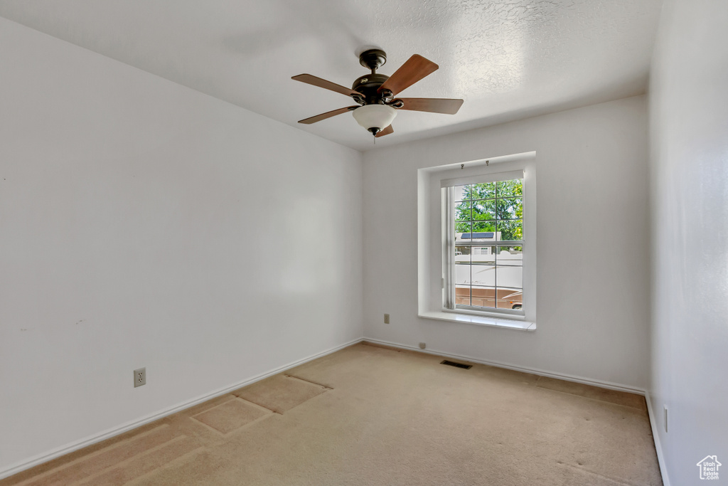 Spare room featuring light colored carpet and a ceiling fan