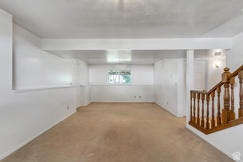 Unfurnished room featuring light carpet, stairway, and a textured ceiling