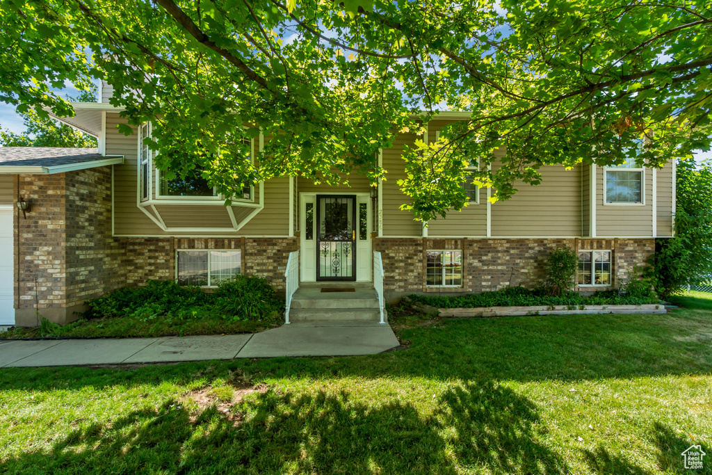 View of front of home with brick siding, a front lawn, and a garage