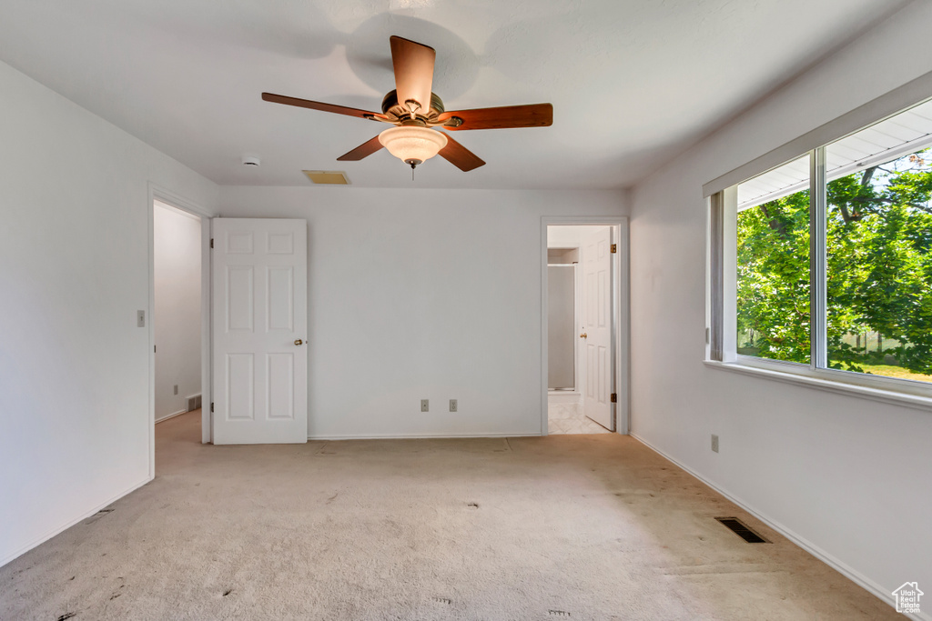 Unfurnished bedroom with carpet, ensuite bathroom, and a ceiling fan