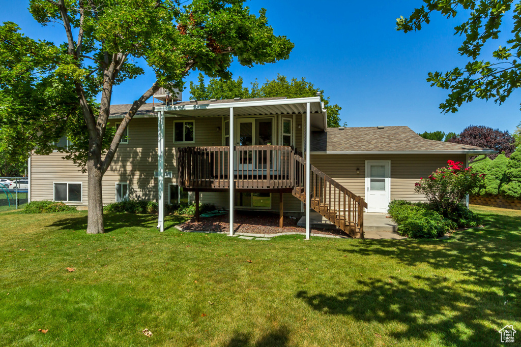 Back of property with a wooden deck, a yard, a shingled roof, and stairs