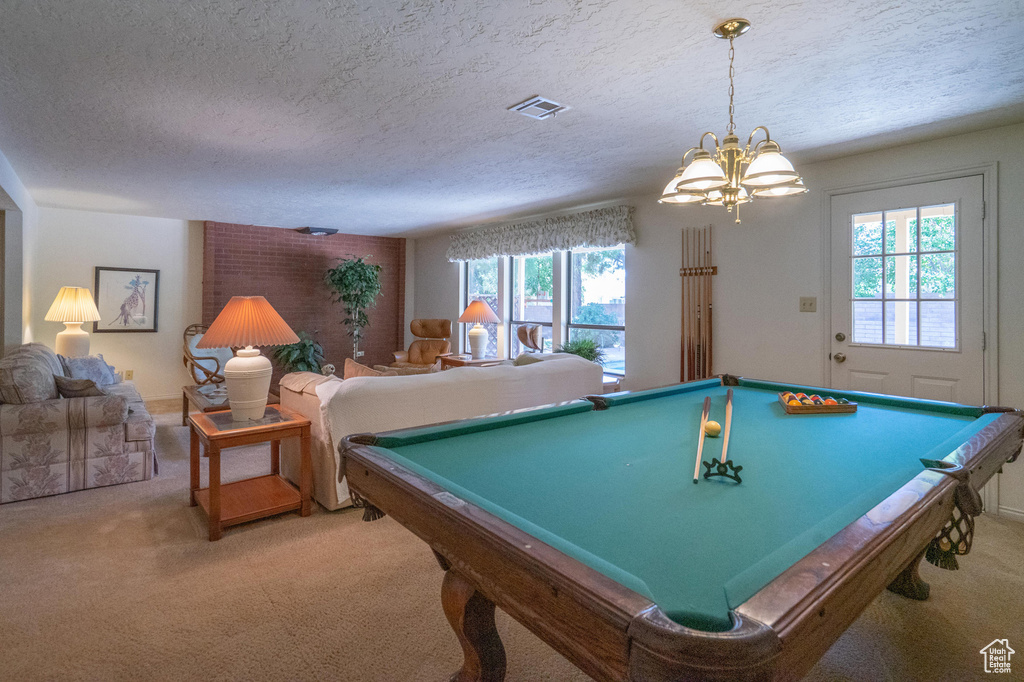 Game room with carpet flooring, a textured ceiling, a chandelier, and billiards