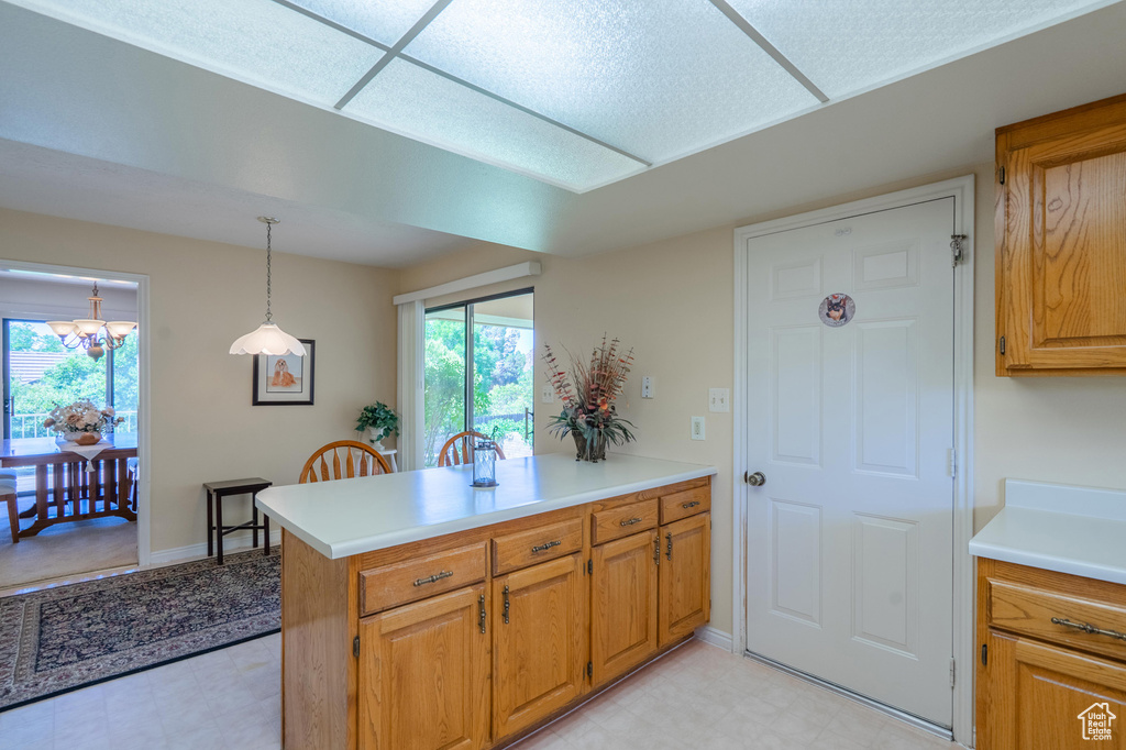 Kitchen featuring a peninsula, light countertops, decorative light fixtures, brown cabinets, and a chandelier