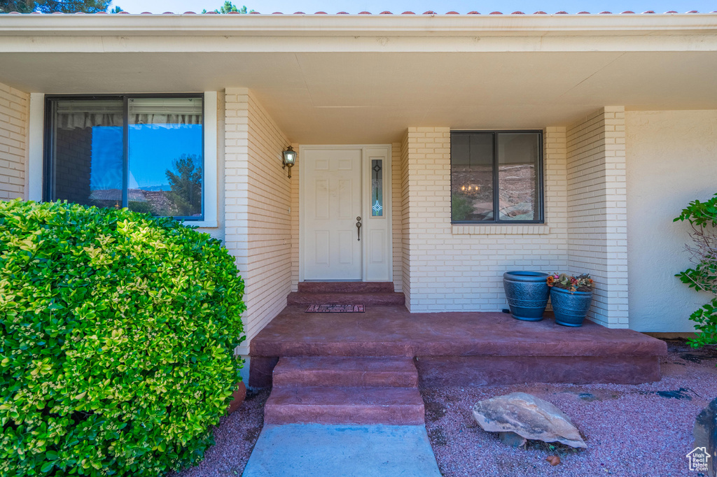 View of exterior entry with brick siding and a porch