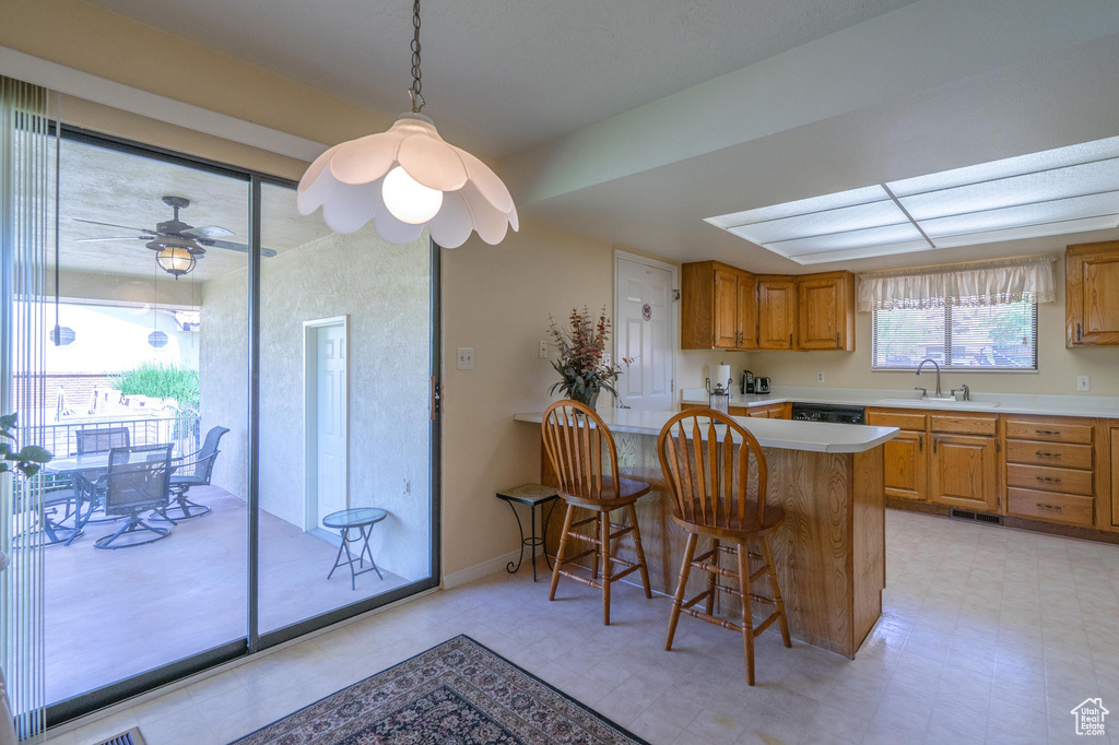 Kitchen with light countertops, a peninsula, light flooring, a breakfast bar, and brown cabinetry