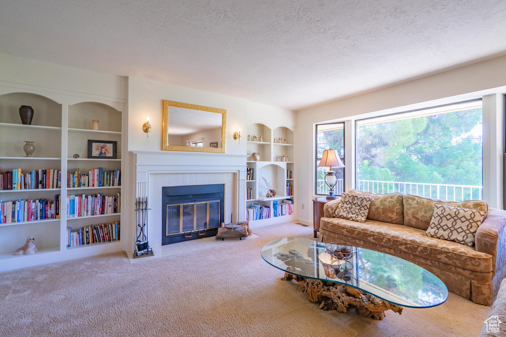 Carpeted living room featuring a textured ceiling, a fireplace, and built in shelves