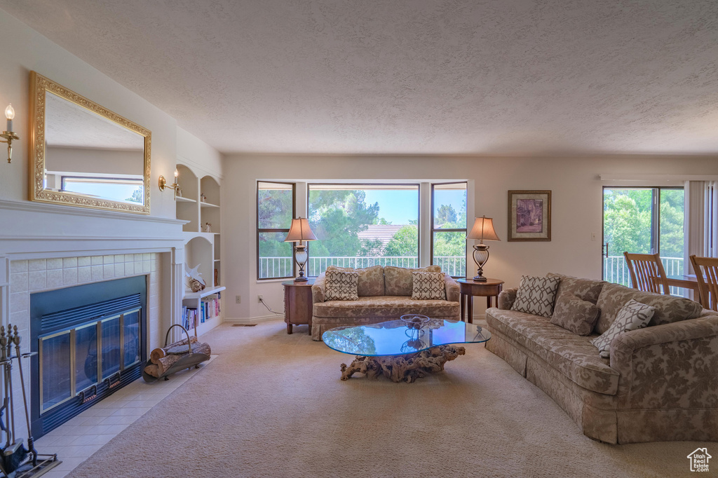 Carpeted living area with a textured ceiling, a fireplace, and built in features