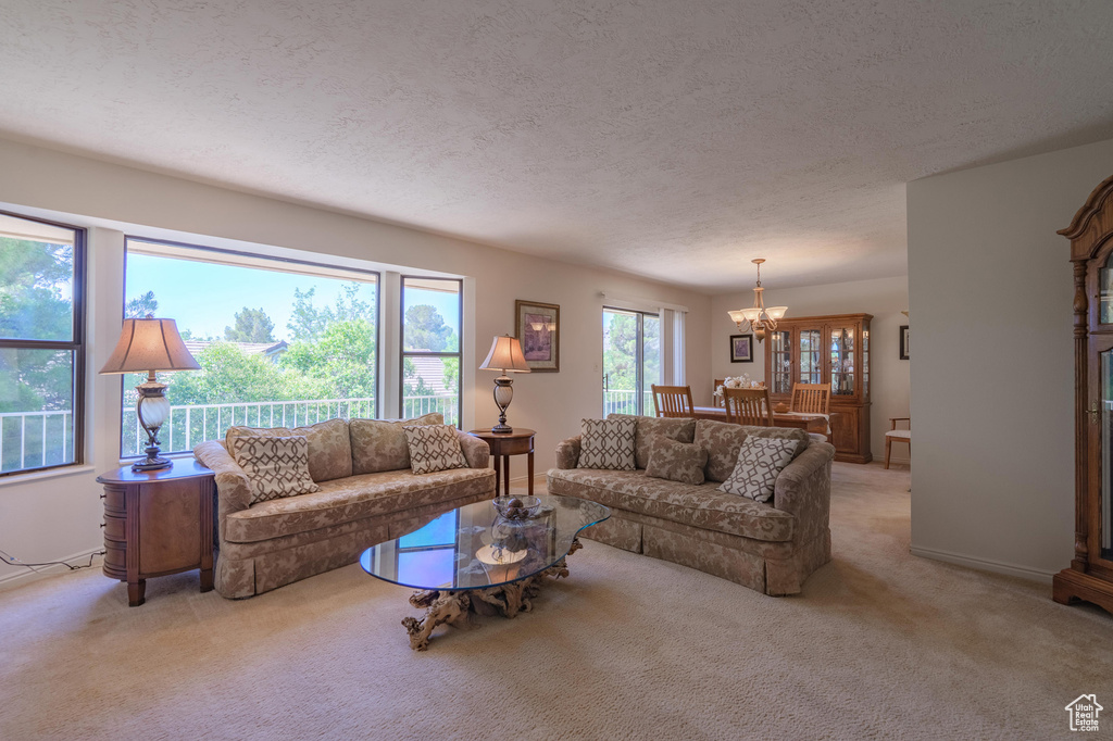 Living room with a chandelier, light carpet, and a textured ceiling
