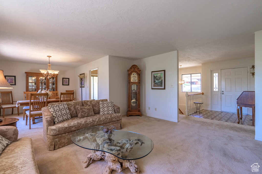 Living area with light carpet, a chandelier, and a textured ceiling