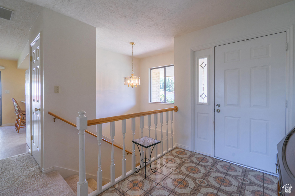 Foyer featuring a textured ceiling and a chandelier