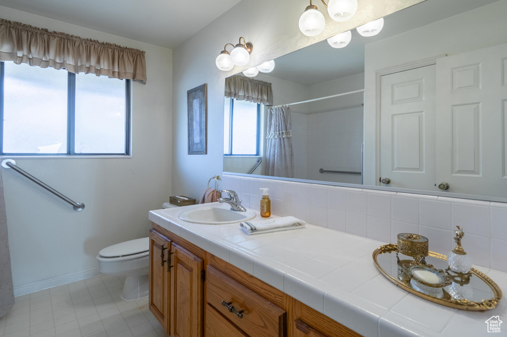 Bathroom featuring double vanity, curtained shower, and tile patterned flooring