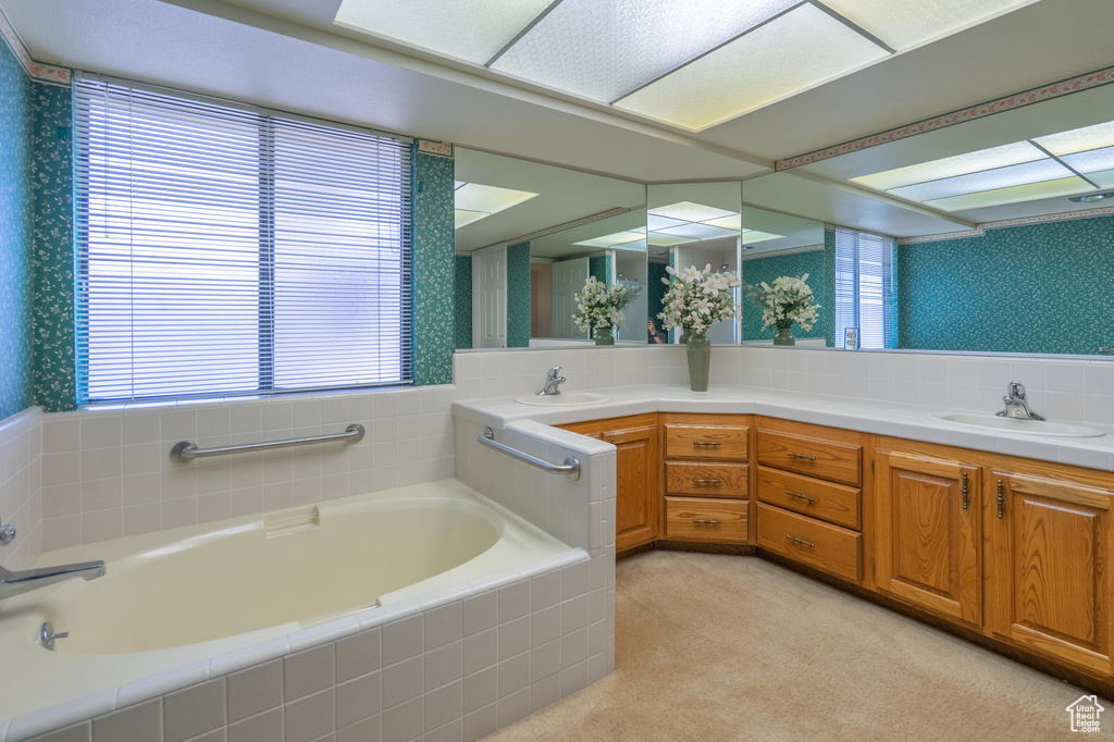 Full bathroom featuring wallpapered walls, a bath, and double vanity