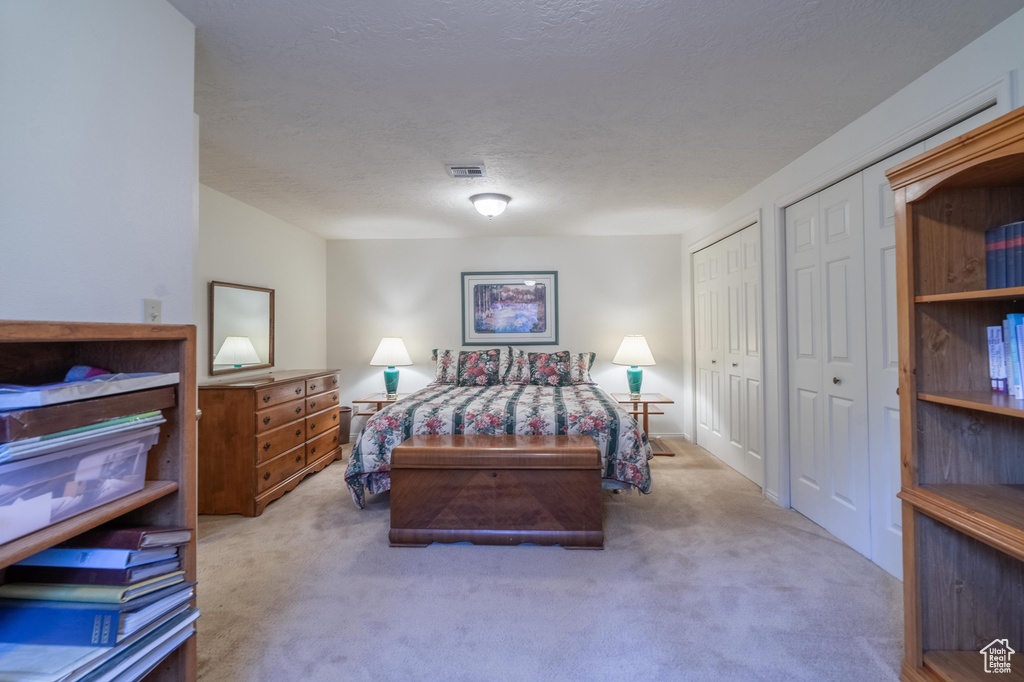 Bedroom with multiple closets, carpet flooring, and a textured ceiling