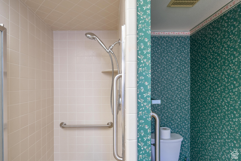 Bathroom with wallpapered walls and tiled shower