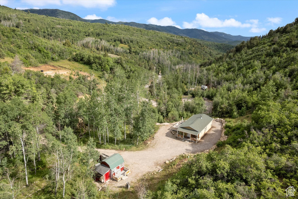 Aerial view of property and surrounding area featuring a forest and a mountain backdrop