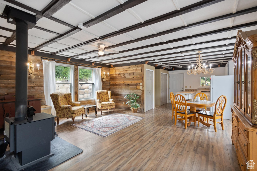 Dining room featuring wood walls, a wood stove, wood finished floors, and a chandelier