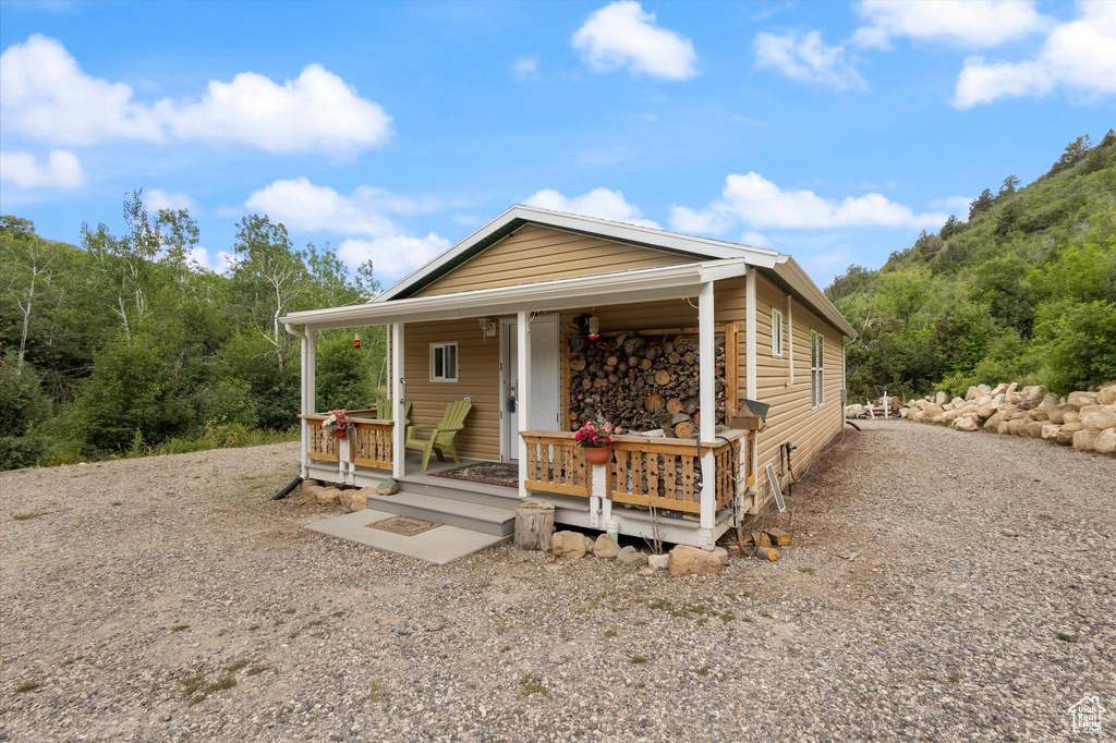 View of front of home with gravel driveway and a porch