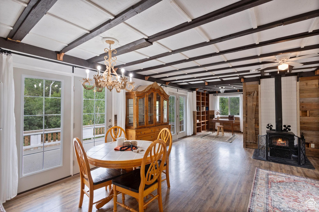 Dining area featuring a wood stove, light wood finished floors, a chandelier, and wooden walls