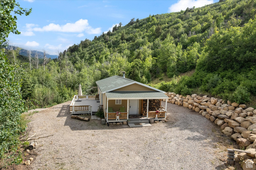 Back of property featuring a forest view, a mountain view, and a porch