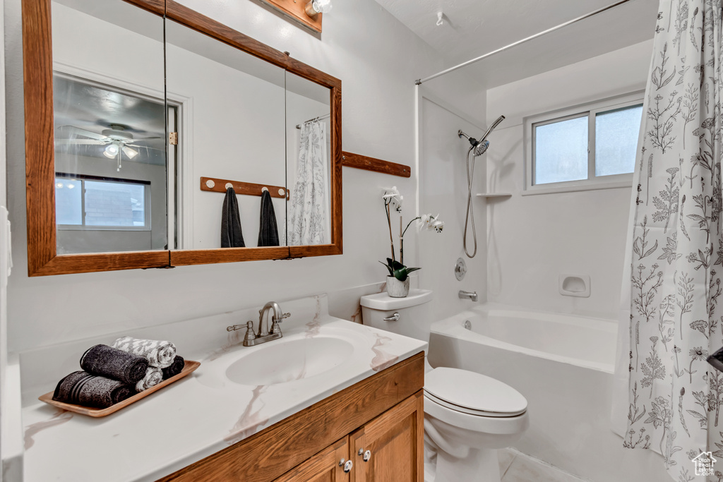 Full bath featuring vanity, shower / bathtub combination with curtain, and a ceiling fan