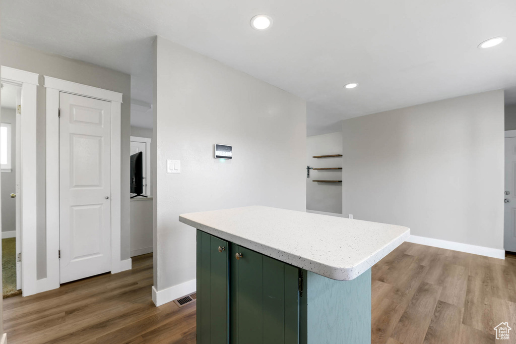 Kitchen with green cabinets, dark wood finished floors, light countertops, a kitchen island, and recessed lighting