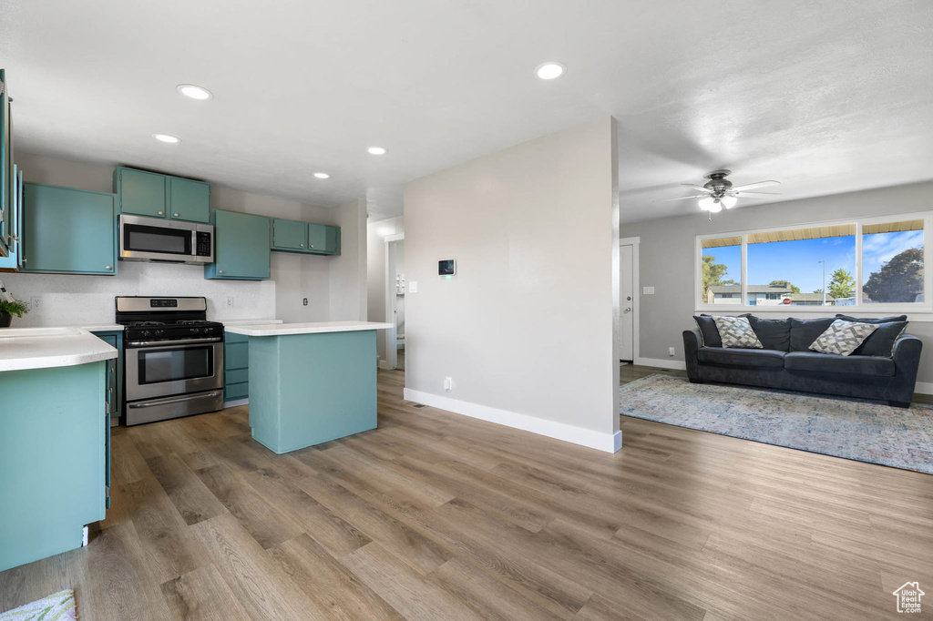 Kitchen featuring appliances with stainless steel finishes, open floor plan, green cabinetry, recessed lighting, and light countertops